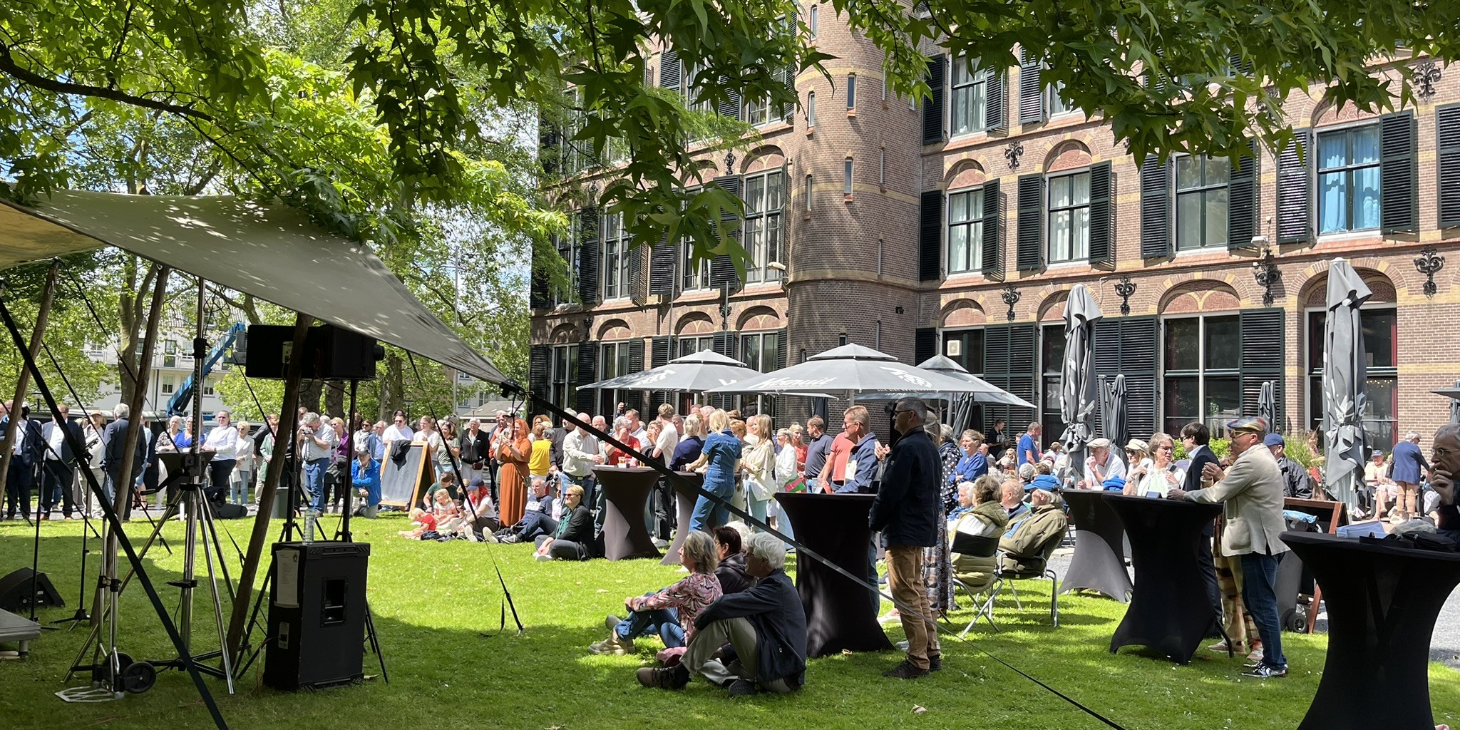 persoon geeft een presentatie voor een groot scherm tenover een volle zaal luisteraars